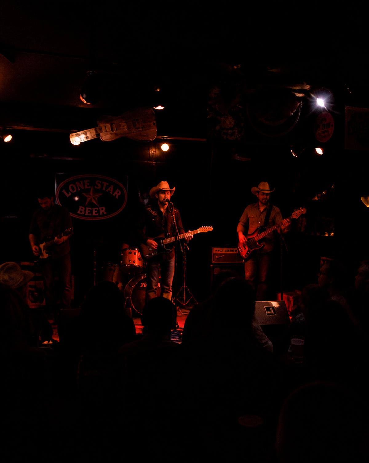 Band playing on a small stage in a dark roadhouse bar